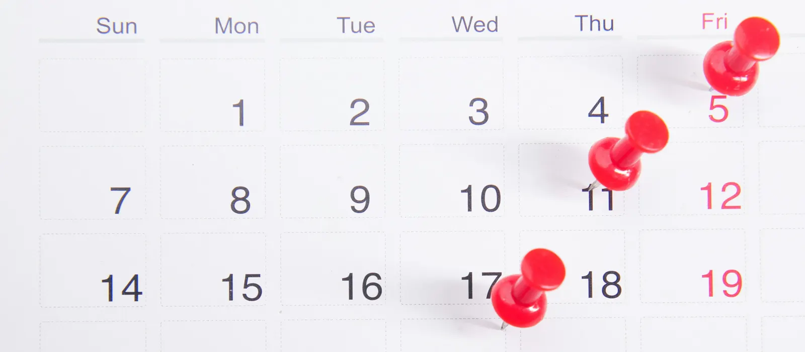 Calendrier avec des épingles rouges, illustration du choix de ne travailler qu'avec 3 clientes par mois