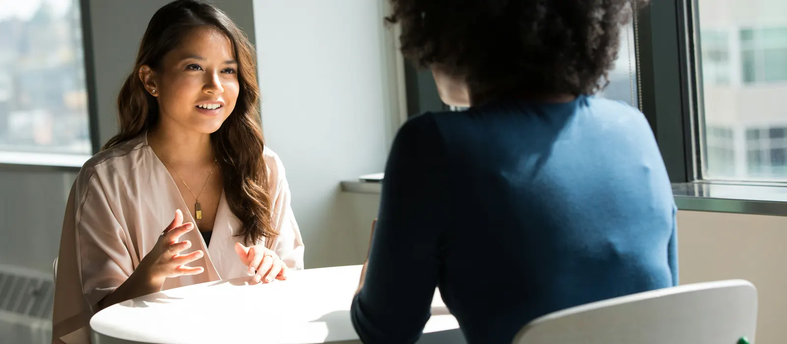 Deux femmes échangent autour d'une table, illustration du rôle d'un coach stratégique