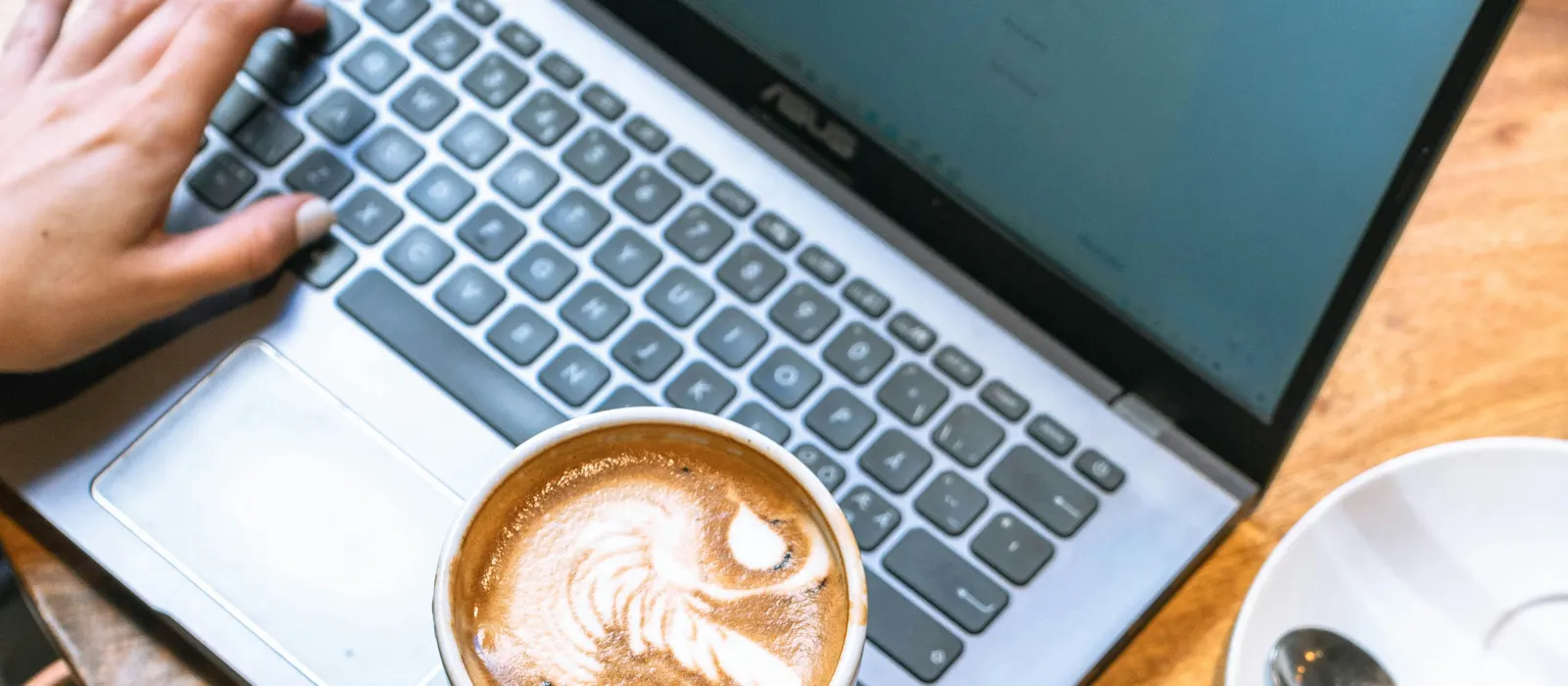 Main tenant un café au-dessus d'un clavier d'ordinateur, illustration freelance vs entrepreneuse