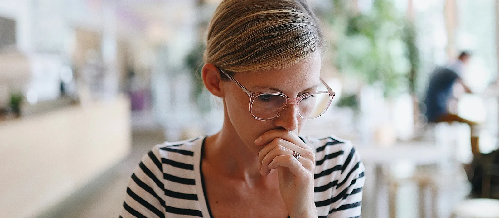 Femme pensive le regard baissé, illustration du syndrome de l'imposteur chez les entrepreneuses
