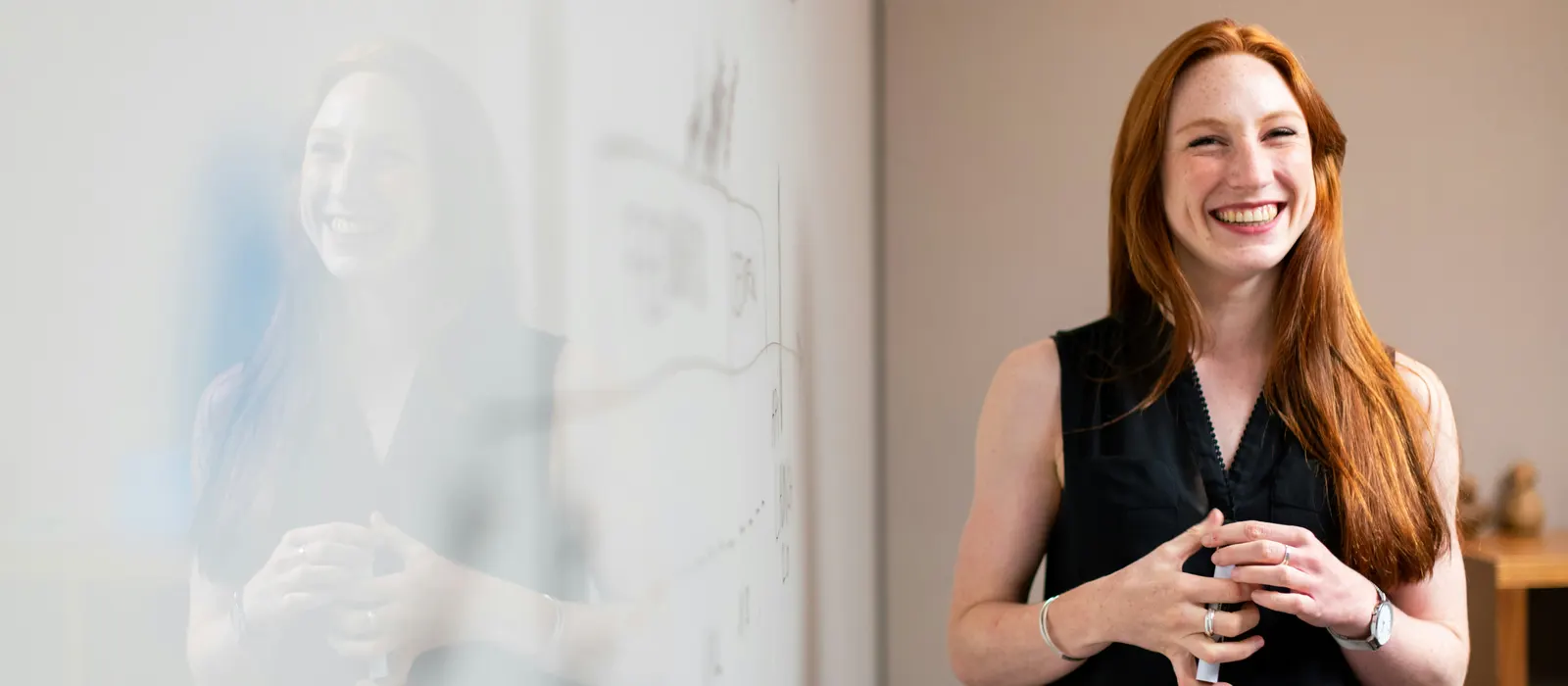 Femme souriante devant un tableau blanc de présentation, illustration de comment pitcher son projet
