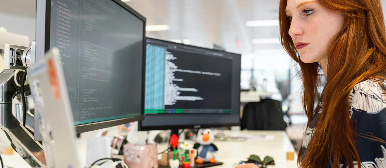 Femme concentrée devant des écrans de code, illustration de la reconversion vers la tech au féminin